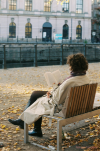 Femme assise sur un banc en train de lire dans un parc, illustration d’une pause mentale pour réguler le système nerveux.