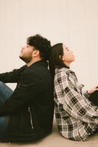 Couple assis dos à dos les yeux fermés pratiquant une pause respiratoire synchronisée pour favoriser la co-régulation émotionnelle